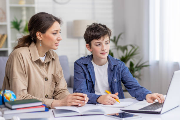 Tutor guiding a teenage student on a laptop