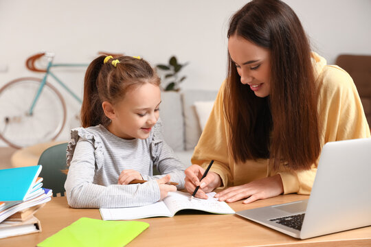 Mother helping her daughter with schoolwork at home